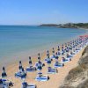 Ombrelloni e lettini blu su una spiaggia deserta.