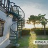 Scale a chiocciola esterne tra due bungalow bianchi al tramonto.