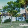 Complesso di bungalow bianchi tra alberi e arbusti in un'area verde.