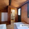 Stanza in legno con bagno, due letti singoli e un armadio bianco.