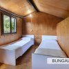 Due letti singoli in una stanza di legno con finestra e luce sul soffitto.