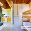 Interno di bungalow con letti a castello e area cucina colorata.