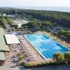 Vista dall'alto di un complesso con piscina, ombrelloni e verde attorno.
