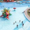 Piscina con giochi d'acqua per bambini, scivoli colorati e persone che si rinfrescano.