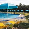 Piscina all'aperto con lettini gialli e ombrelloni azzurri.