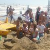 Bambini e adulti giocano sulla spiaggia vicino al mare mosso.
