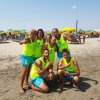 Gruppo di persone in divise gialle sulla spiaggia.