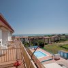 Balcone di un edificio con vista su una piscina e il mare in lontananza.