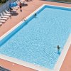 Piscina rettangolare con lettini e alcune persone in acqua.