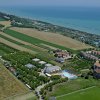Vista aerea di campagna con campi, edifici e piscina vicino al mare.