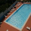 Una piscina rettangolare con sdraio e ombrelloni lungo i bordi.
