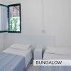 Camera con due letti singoli e finestra aperta, pareti bianche.