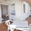 Terrazza con tavolo bianco e sedie, ingresso a un appartamento.