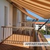 Balcone con tende a strisce e vista sul mare.