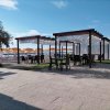 Tettoie in legno con tavoli e sedie vicino alla spiaggia.