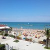Una spiaggia con ombrelloni arancioni, mare calmo e cielo blu.