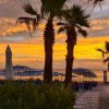 Tramonto colorato su spiaggia con palme.