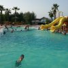 Piscina con scivoli gialli e persone che nuotano.