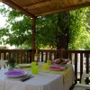 Tavolo apparecchiato su terrazza coperta con vista sul giardino.
