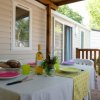 Tavolo apparecchiato su terrazza esterna con cibo, vino e barbecue.