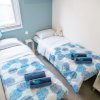 Due letti singoli con lenzuola blu, due asciugamani e un peluche.