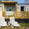 Due lettini prendisole davanti a una casa mobile con veranda in legno chiaro.
