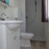 Bagno con lavabo, WC e doccia. Armadietto e specchio sopra il lavabo. Pavimento in legno chiaro.