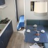 Cucina e sala da pranzo in una casa mobile, tavolo apparecchiato e divano blu a L.