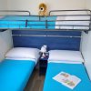Cameretta con due letti singoli, un letto a castello con peluche e un libro sul letto.
