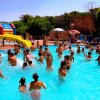 Persone che si divertono in una piscina con uno scivolo giallo.