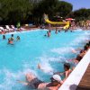 Persone in una piscina partecipano a un'attività con uno scivolo giallo.