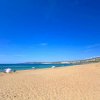 Una spiaggia sabbiosa con ombrelloni colorati e mare calmo sotto un cielo limpido.