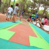 Bambini vicino a un percorso di minigolf tra gli alberi.