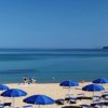 Una spiaggia con ombrelloni blu e un mare calmo.
